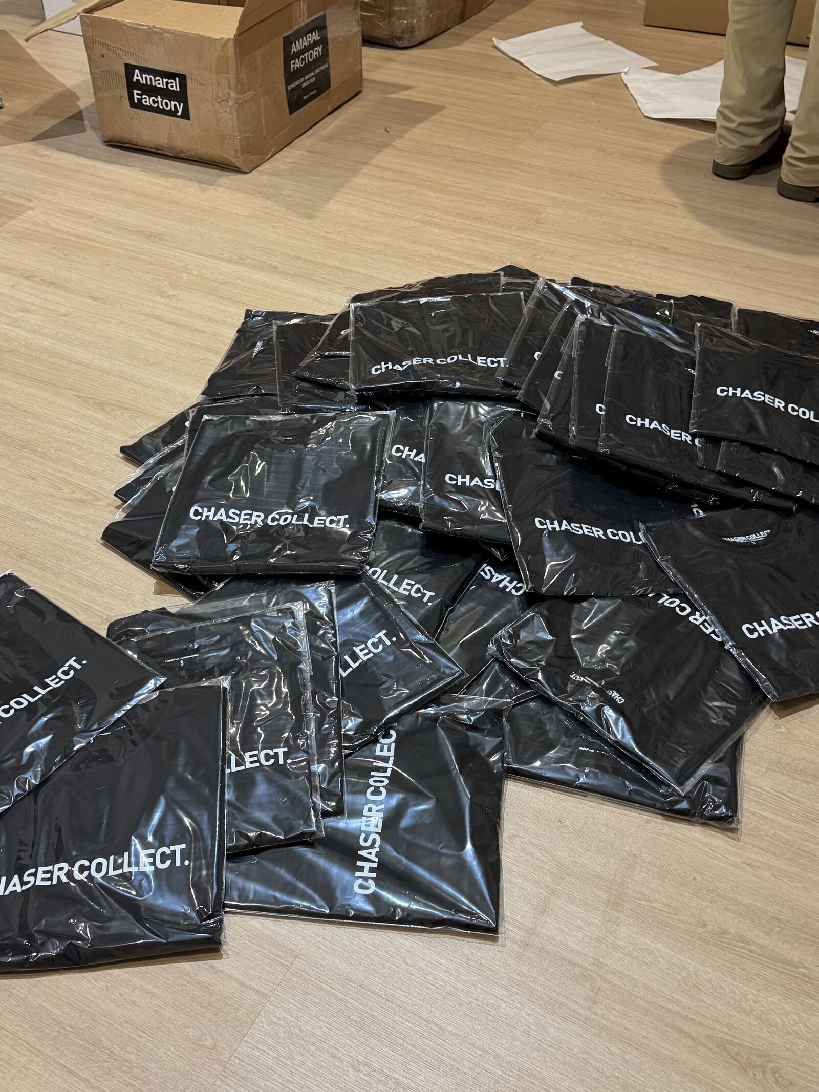 Bulk branded poly mailer bags alongside Amaral Factory shipping boxes