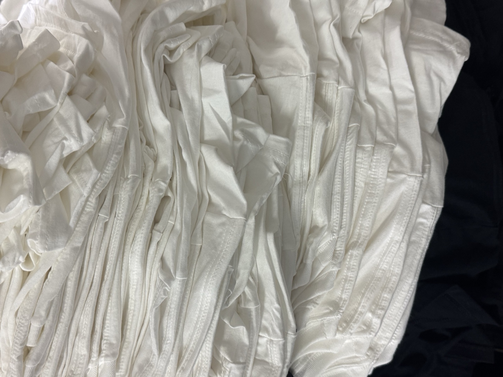 Bulk stack of white cotton t-shirt bodies bundled together during production before finishing