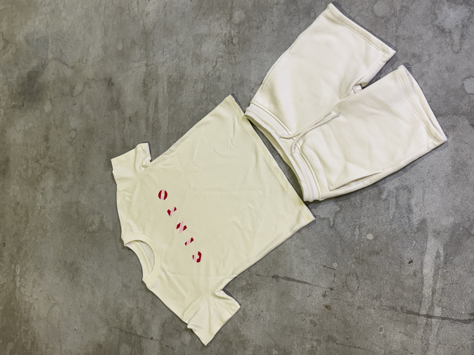 Off-white baby t-shirt with small red curved text paired with matching off-white fleece jogger trousers