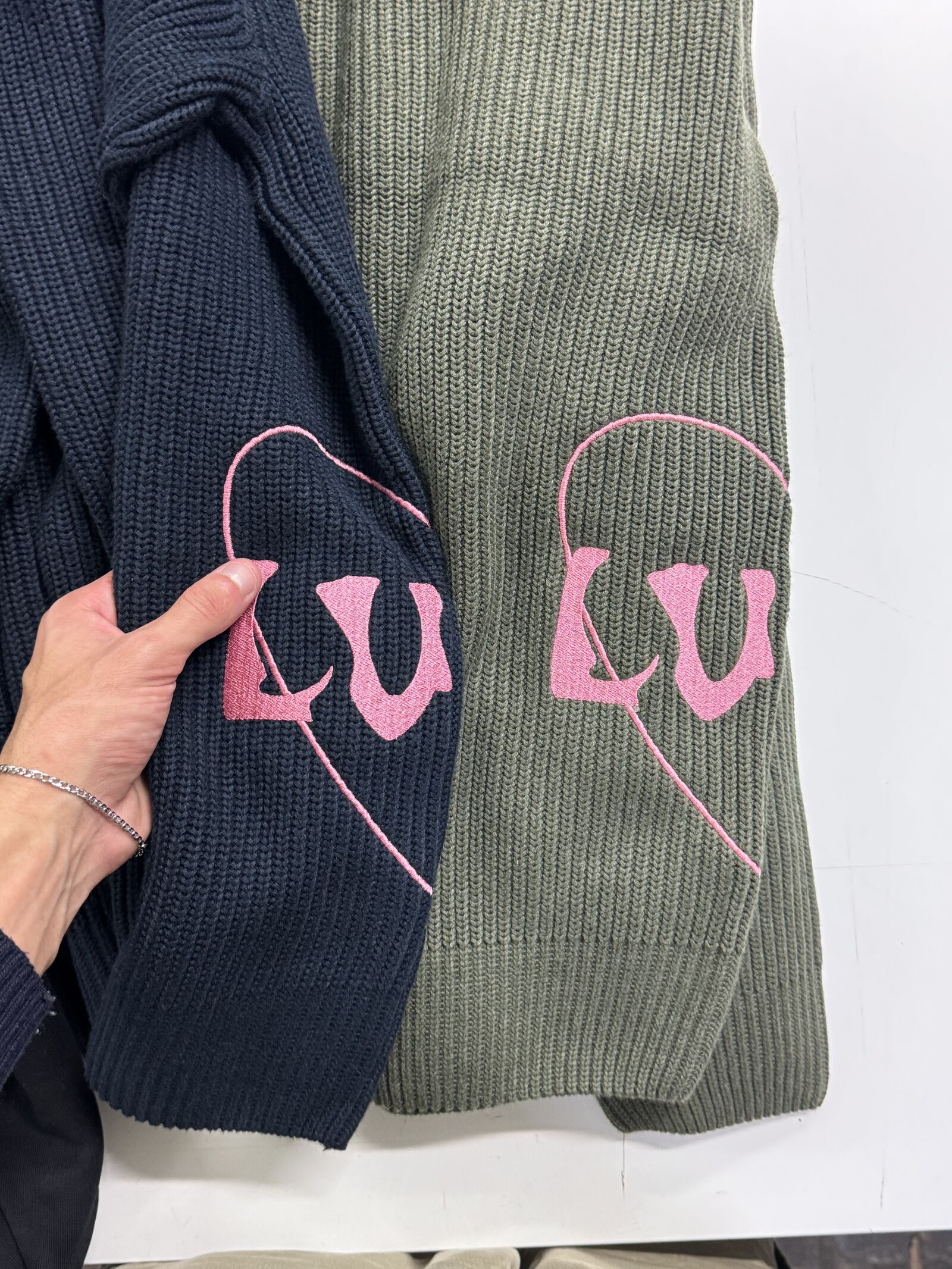 Chunky knit scarves in olive green and navy with pink intarsia logos