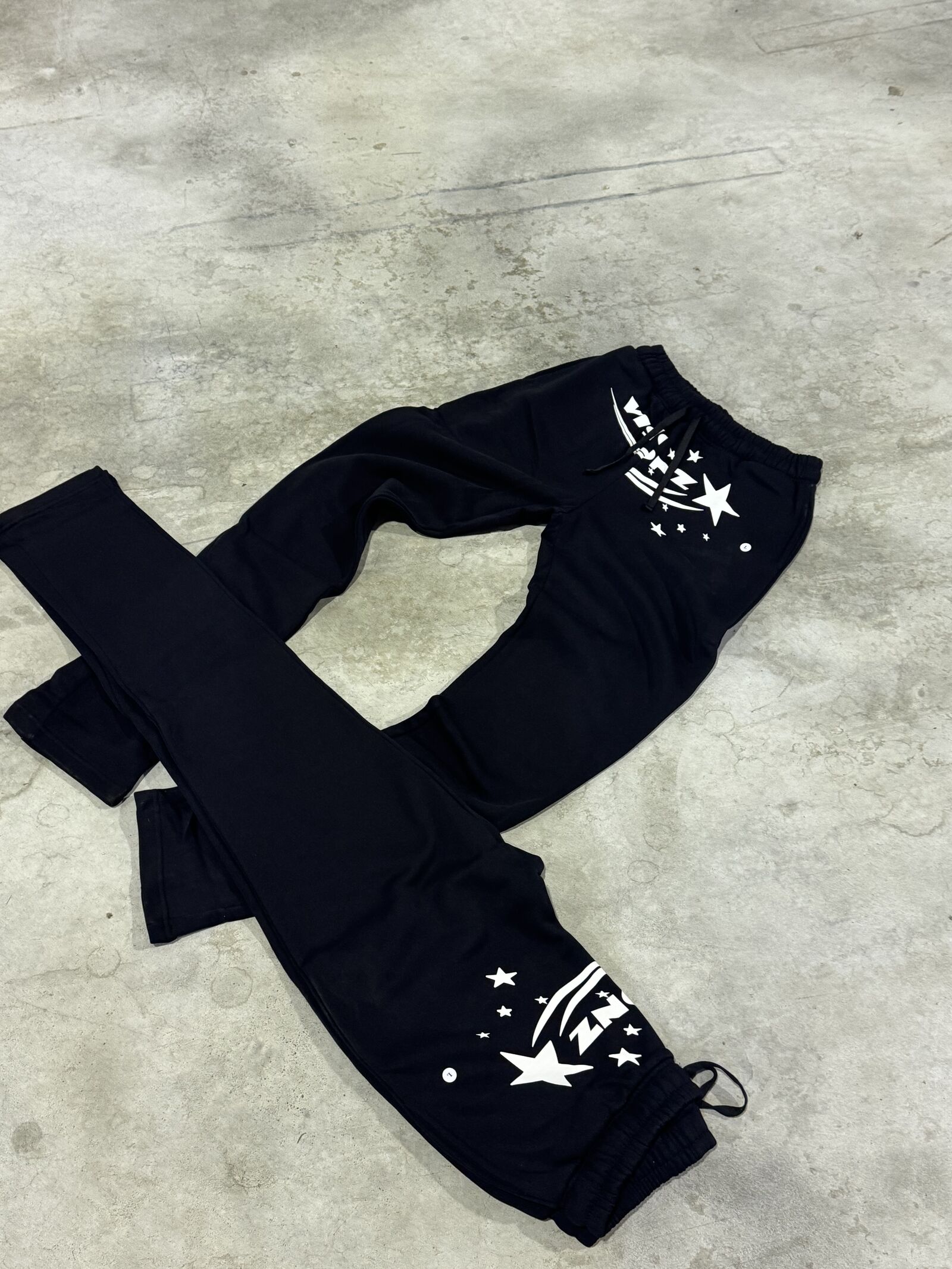 Two pairs of black flared joggers with bold white star and graphic print
