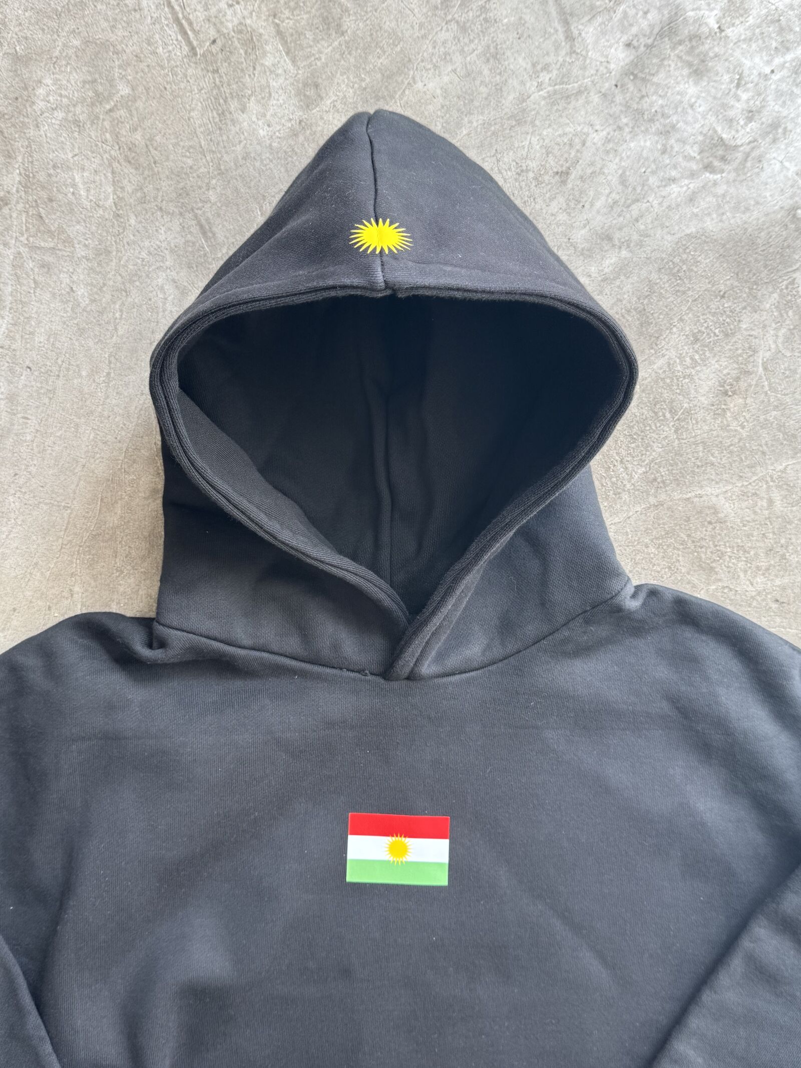 Black heavyweight hoodie with flag patch and yellow embroidered sun on hood