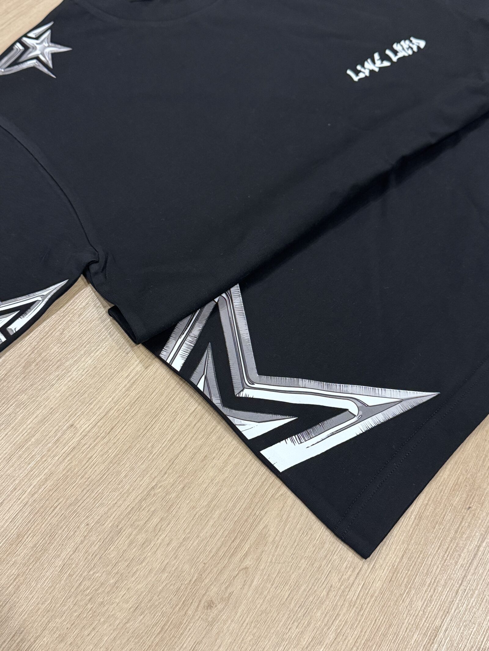 Black t-shirts with metallic silver star print on wooden surface